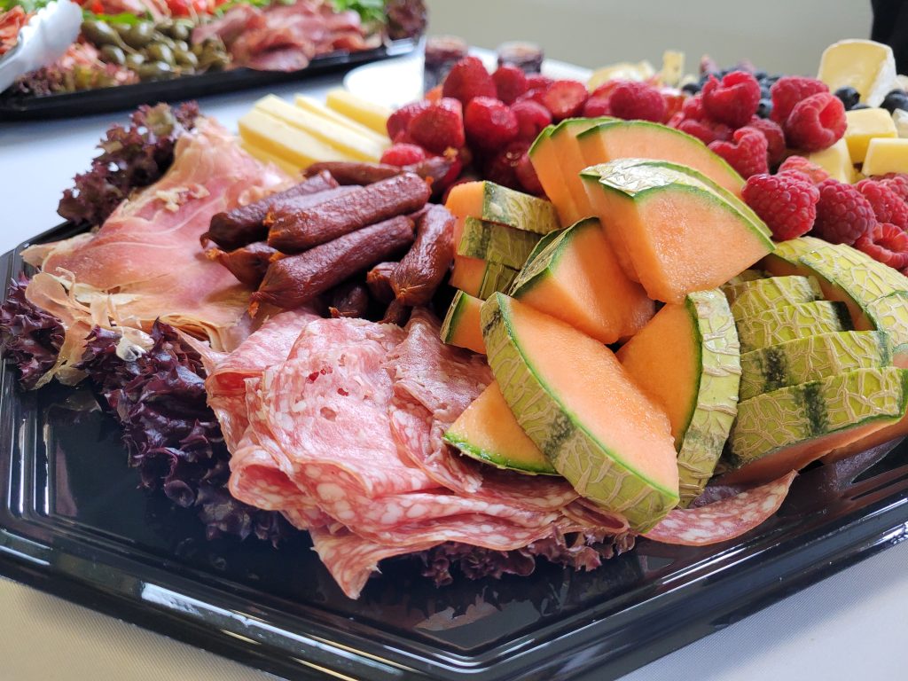 A plate of food, fruits and salami